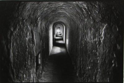 A stone arched tunnel with light at the end.